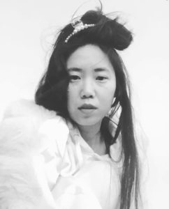 a person in a white dress in a black and white photo with long black hair half tied up with a clip