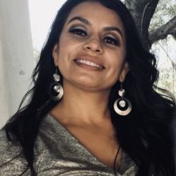 Norell Martinez smiling wearing a grey top and big silver earrings